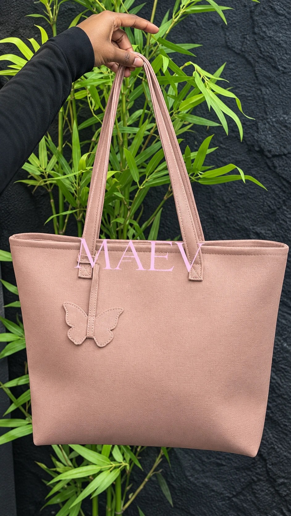 A mauve MAEV tote held up against green bamboo